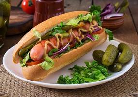 cachorro-quente com picles, tomate e alface em fundo de madeira foto