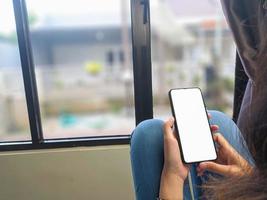 close-up de uma mão de mulher segurando uma tela branca de smartphone é .mockup em branco. foto