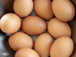 close-up de feliz páscoa, olhando para um frango cru marrom fresco, vários ovos em uma tigela prateada separando os ovos em um piso de gesso colorido. para cozinhar alimentação saudável foto
