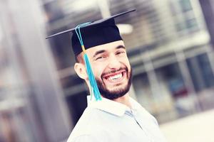 graduado alegre fora do edifício moderno foto