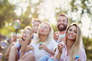 feliz grupo de amigos soprando bolhas ao ar livre foto