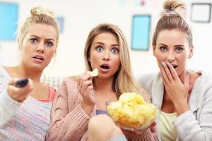 três mulheres bonitas assistindo tv em casa foto