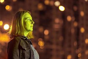 retrato de uma jovem em uma cidade noturna em verde neon em uma noite de verão. luzes da cidade foto