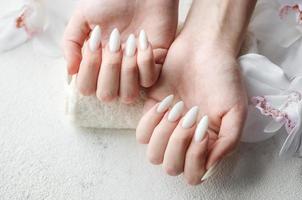 mãos de uma jovem com manicure branca nas unhas foto