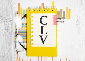 clv - valor vitalício do cliente - texto como um símbolo no caderno amarelo foto