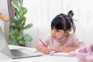 menina asiática em casa fazendo lição de casa foto