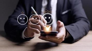 conceito de avaliação de serviço ao cliente. usando um smartphone está pressionando o emoticon de rosto sorrindo de satisfação na tela de toque virtual. foto