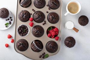 muffins de chocolate em uma forma de muffin com framboesas foto