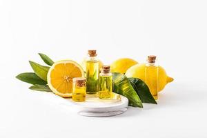 um conjunto de frascos de vidro com rolha com um produto à base de óleo essencial de limão sobre uma bandeja de gesso branco entre limões e folhas. foto
