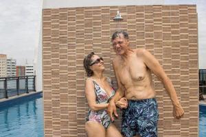 casal enxaguando em um chuveiro à beira da piscina foto