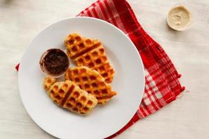 croissant waffle ou croffle com calda de chocolate servido em caixa e fundo branco foto