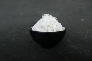 bihun ou aletria ou macarrão de arroz ou cabelo de anjo isolado em fundo preto. servido em tigela pequena foto