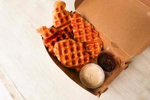 croissant waffle ou croffle com calda de chocolate servido em caixa e fundo branco foto