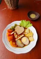 selat solo é uma salada tradicional da indonésia. feito de ovos cozidos, grão de bico cozido, cenoura cozida, batatas fritas e alface, bife ou bistik. servido na mesa de madeira foto