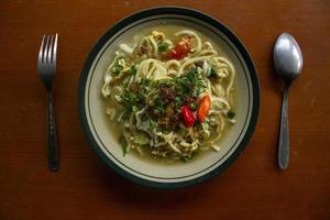 mie godog jawa ou bakmi jawa ou macarrão java ou mie rebus ou macarrão cozido com colher e garfo. macarrão de comida de rua tradicional indonésio de java, indonésia em fundo branco foto