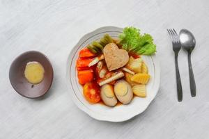 selat solo é uma salada tradicional da indonésia. feito de ovos cozidos, grão de bico cozido, cenoura cozida, batatas fritas e alface, bife ou bistik. servido na mesa de madeira foto