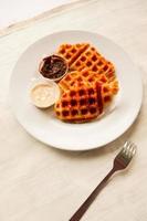 croissant waffle ou croffle com calda de chocolate servido em caixa e fundo branco foto