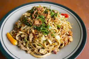 mie goreng jawa ou bakmi jawa ou macarrão java com colher e garfo. macarrão de comida de rua tradicional indonésio do centro de java ou yogyakarta, indonésia em fundo branco foto