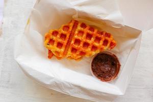 croissant waffle ou croffle com calda de chocolate servido em caixa e fundo branco foto