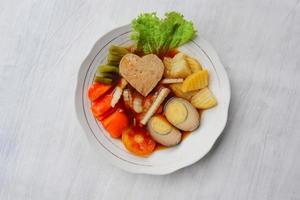 selat solo é uma salada tradicional da indonésia. feito de ovos cozidos, grão de bico cozido, cenoura cozida, batatas fritas e alface, bife ou bistik. servido na mesa de madeira foto