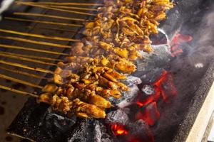 sate ayam ou satay de frango com bolo de arroz lontong servido com molho de amendoim, pimentão fatiado e chalota. foto com foco seletivo