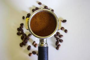 porta filtro com café moído e grão de café isolado de um fundo branco foto