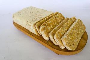 tempeh cru ou tempe. fatias de tempeh em fundo branco. sementes de soja crua. tempe é um alimento tradicional indonésio feito de soja fermentada. foto