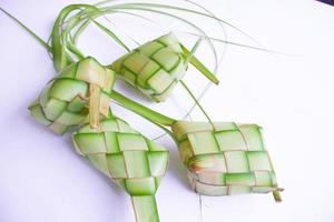 ketupat em prato de barro isolado no fundo branco. bolinho de arroz ketupat é comida servida quando idhul fitri eid mubarak na indonésia, feito de arroz envolto em folhas de coco jovem janur foto