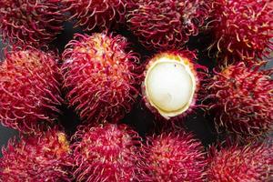 rambutan, doce fruta vermelha rambutan isolada em fundo preto foto