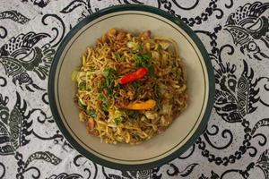 mie goreng jawa ou bakmi jawa ou macarrão java com colher e garfo. macarrão de comida de rua tradicional indonésio do centro de java ou yogyakarta, indonésia em fundo branco foto