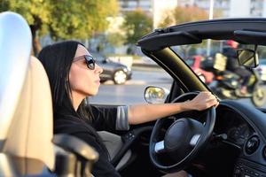 mulher bonita feliz dirigindo um carro esportivo conversível na cidade foto