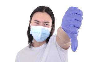 modelo masculino asiático usando e segurando máscara facial cirúrgica e luvas de proteção foto
