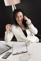 mulher de negócios linda sentada em seu escritório e falando no celular. conceito de negócios foto