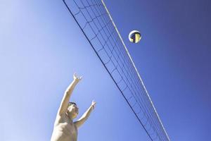 garoto joga vôlei em lindo dia de verão foto