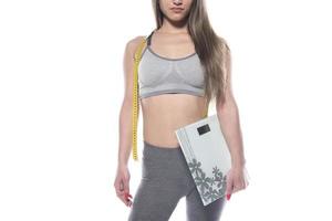 modelo feminino segurando escala e fita métrica sobre fundo branco foto