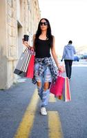 mulher bonita andando na rua com sacolas de compras. modelo feminino na moda na cidade segurando sacolas de compras. foto