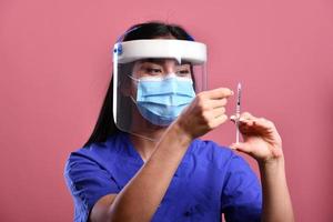 closeup médica asiática usando escudo facial e traje de proteção individual para surto de coronavírus foto