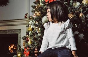 menina asiática decora a árvore de natal dentro de casa. na manhã antes do natal. garota amorosa retrato close-up. foto