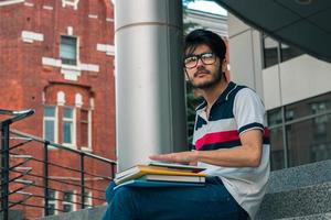 cara pensativo bonito em copos segurando um livro foto