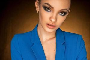 linda jovem de casaco azul com maquiagem de beleza no estúdio foto