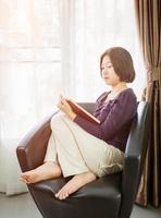 cabelo curto jovem mulher asiática leu um livro na sala de estar foto