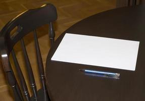 papel em branco com uma caneta na mesa em casa. vista lateral foto