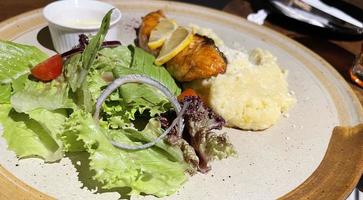 peixe salmão grelhado defumado servido com salada e purê de batata com limão foto