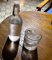 refrescante vodka gelada na garrafa com pedras de gelo no copo servido no pub foto