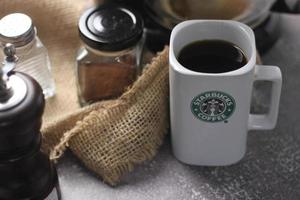 Washington, EUA - 30 de setembro de 2022 - caneca de cerâmica Starbucks. coloque a mesa cinza e a cafeteira, a cafeteira, o moedor de café, os grãos de café moídos. foto