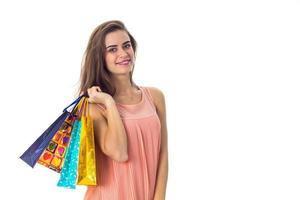 linda garota tem em uma mão um monte de pacotes com compras isoladas no fundo branco foto