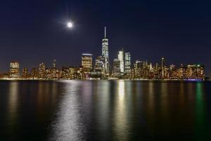 o horizonte de nova york visto do outro lado do rio hudson em nova jersey ao entardecer com a super lua ao fundo. foto