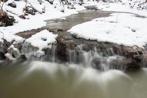 um pequeno rio de floresta rochosa no inverno foto