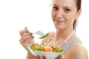 retrato de uma jovem linda que sorri e come salada foto