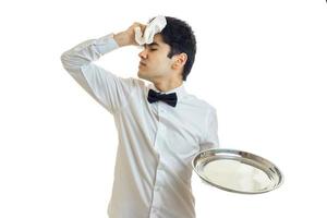 homem moreno cansado garçom de uniforme com bandeja de prata na mão foto